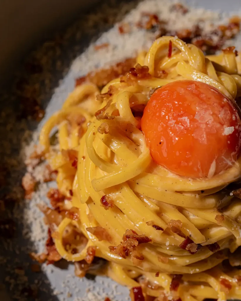 Close-up of a bowl of carbonara topped with cured egg yolk