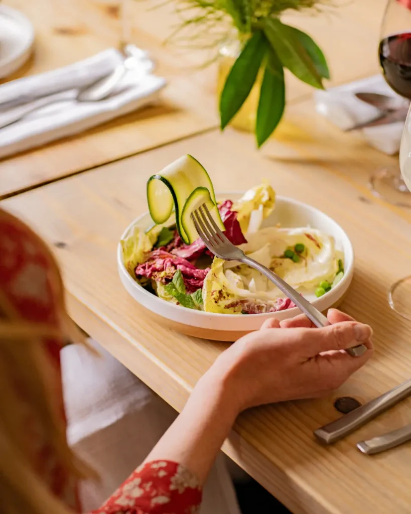 Person seated at a table eating an insalata salad