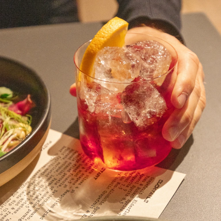 Male hand holding a negroni with a orange garnish