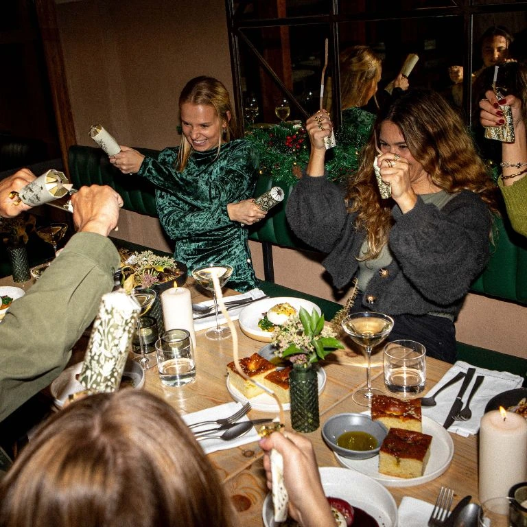 Group of friends laughing and pulling crackers around a table