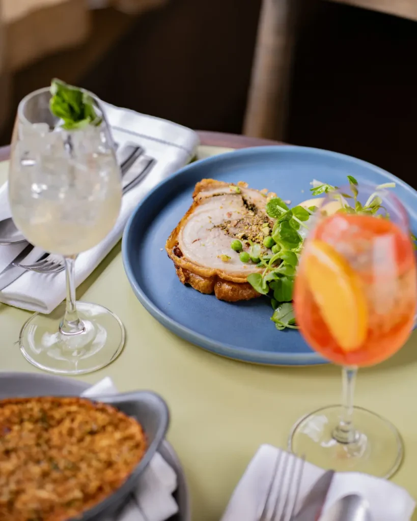 Roast porchetta with seasonal greens on a blue plate